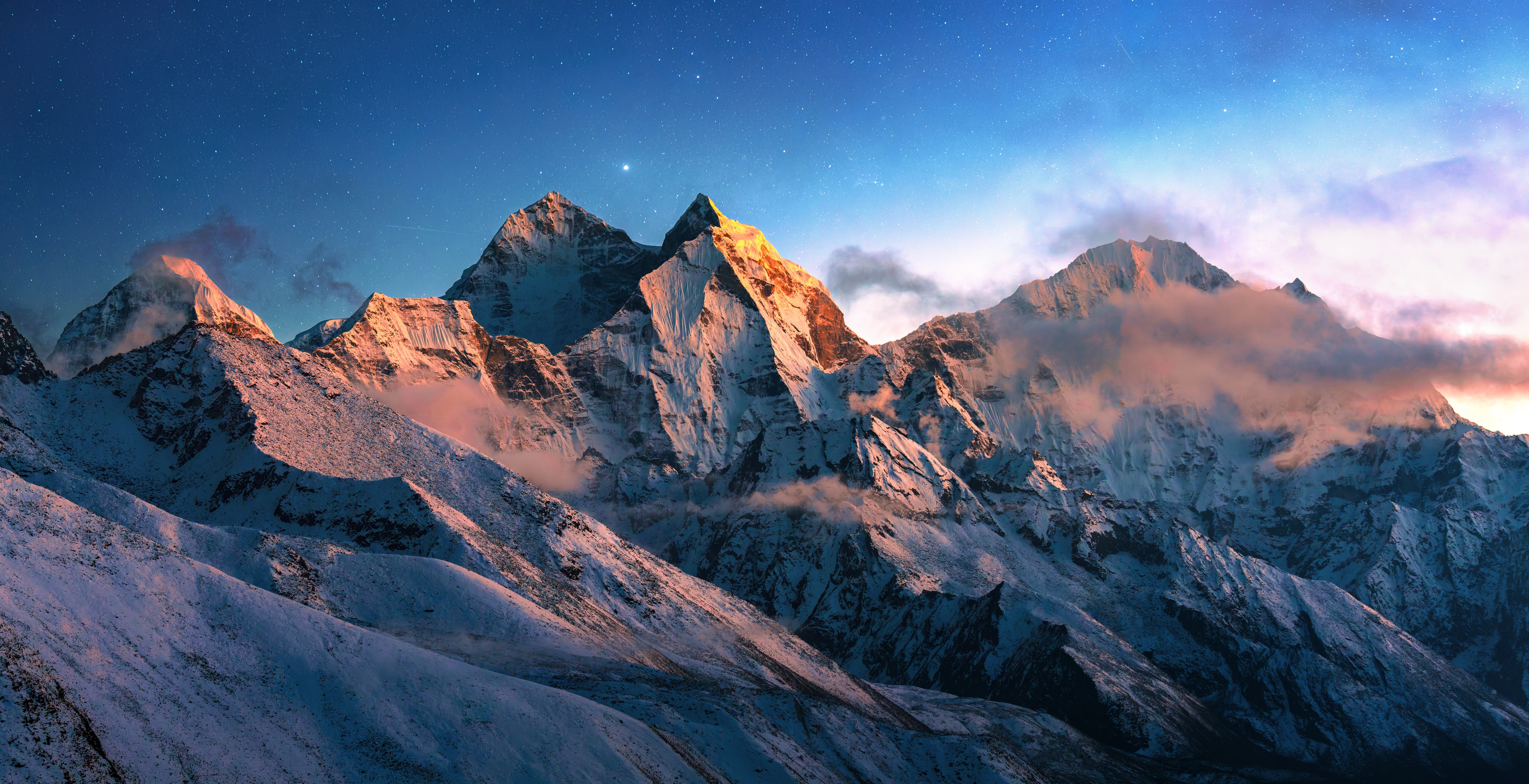 Snow-covered Himalayan peaks in soft dawn light beneath a star-filled sky.